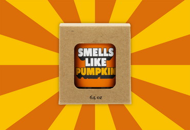 Candle in a box labeled 'Smells Like Pumpkin' on a sunburst background