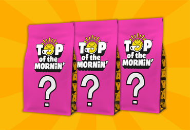 Three bright pink mystery coffee bags standing upright on a yellow sunburst background. Each bag features the 'Top of the Mornin'' logo with a smiling yellow sun and a large white question mark.