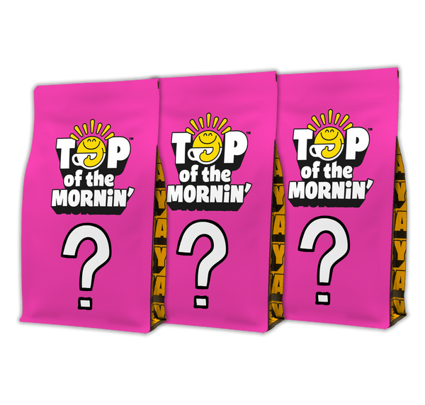 Three bright pink mystery coffee bags with the brand logo 'TOP of the MORNIN'' and a large white question mark on the front, shown on a plain white background.