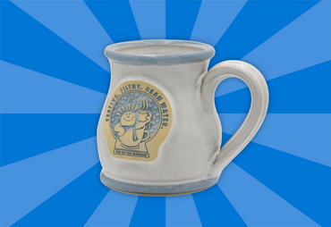 White ceramic mug with a decorative label on a blue radial background